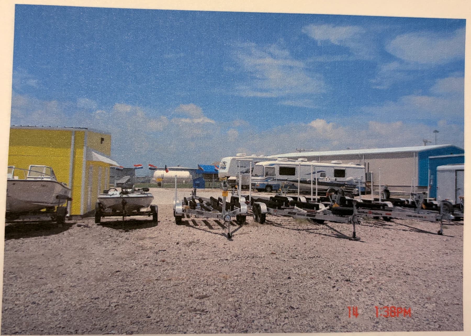 A historical photograph shows RVs, boats, and trailers arranged across the early gravel storage yard.