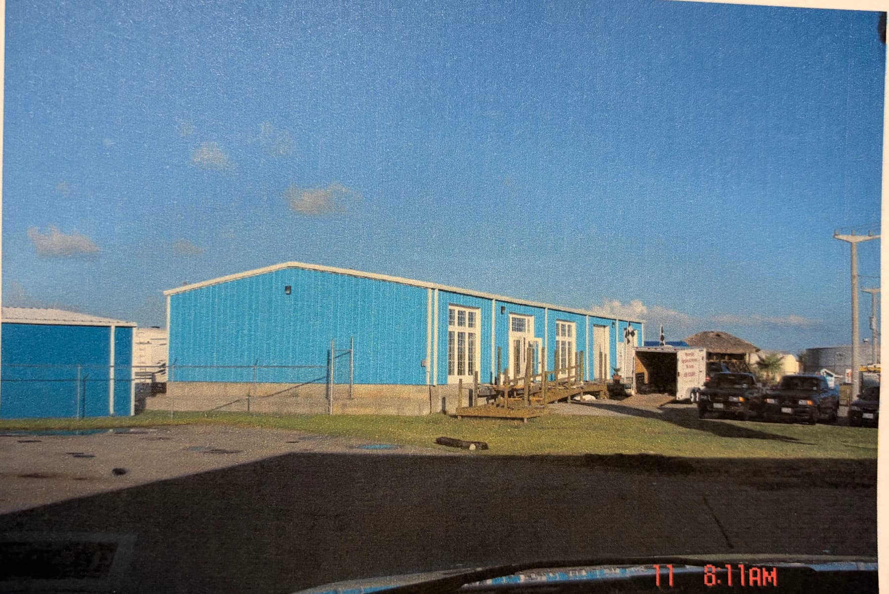 A historical photograph shows the blue Tiki Storage building along the road on Tiki Island.