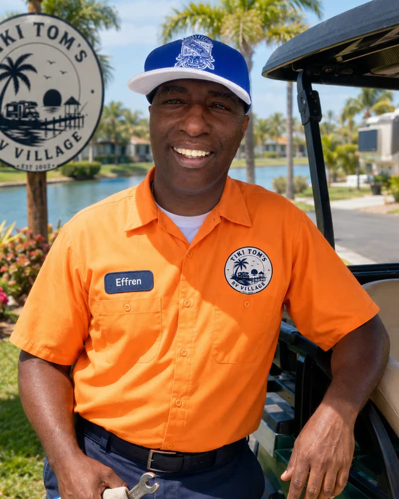 Effren in an orange Tiki Tom’s uniform and cap beside a park cart.