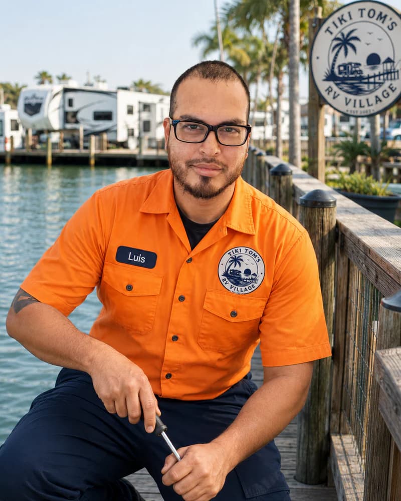 Luis in an orange Tiki Tom’s uniform beside the waterfront and RV sites.
